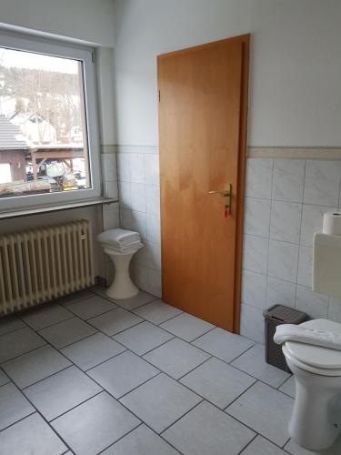 a bathroom with a toilet and a wooden door at Berghotel Natura Bed & Breakfast in Winterberg
