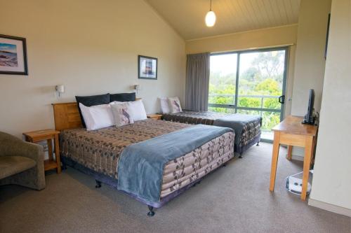 a hotel room with two beds and a balcony at Omau Settlers Lodge Motel in Westport