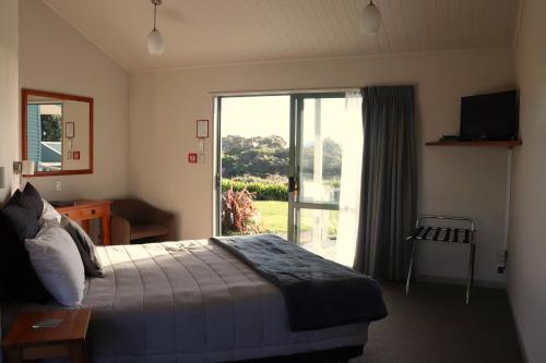 a bedroom with a bed and a sliding glass door at Omau Settlers Lodge Motel in Westport