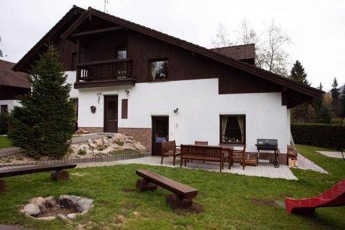 una casa con una mesa de picnic y bancos frente a ella en Holiday home in Harrachov 33511, en Harrachov