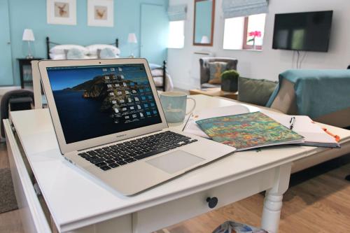 a laptop computer sitting on a table with a book at Cobbler's Cottage in Dunblane