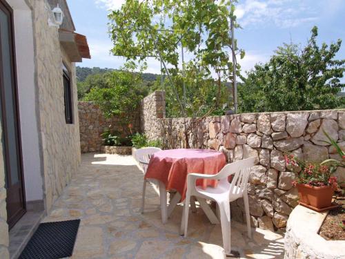 a patio with a table and chairs and a stone wall at Apartment in Veli Losinj 33734 in Veli Lošinj