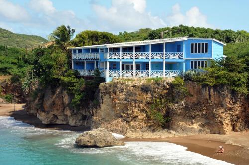 a blue house on a cliff next to the ocean at Blue View Apartments in Sabana Westpunt