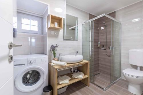 een badkamer met een douche, een wastafel en een wasmachine bij Holiday home in Medulin/Istrien 36032 in Medulin