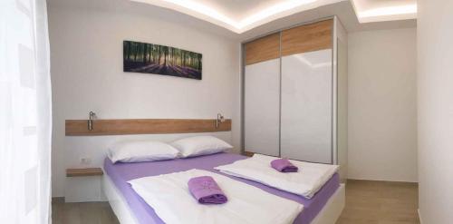 Apartment in Ljubac/Zadar Riviera 31380 في لوجوباك: غرفة نوم مع سرير مع وسادتين أرجوانيتين عليه