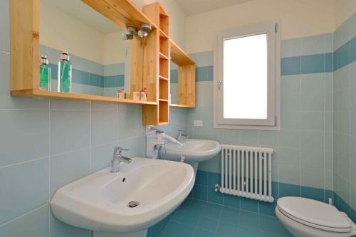 ein Bad mit einem Waschbecken, einem WC und einem Fenster in der Unterkunft Apartments in Lignano 21702 in Lignano Sabbiadoro