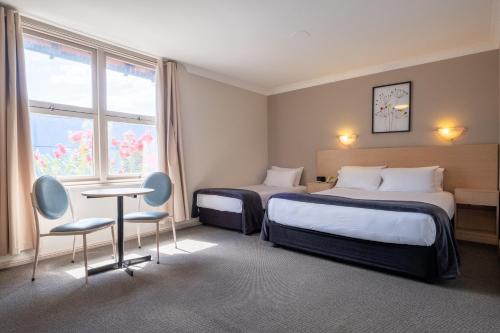 Habitación de hotel con 2 camas, mesa y sillas en Maclin Lodge Motel, en Campbelltown