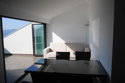 a living room with a white couch and a glass table at The Roof On The Sea in Fondachello
