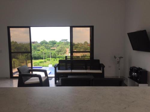 a living room with chairs and a large window at Villa lili, Carmen de Apicala condominio San Simon in Carmen de Apicalá