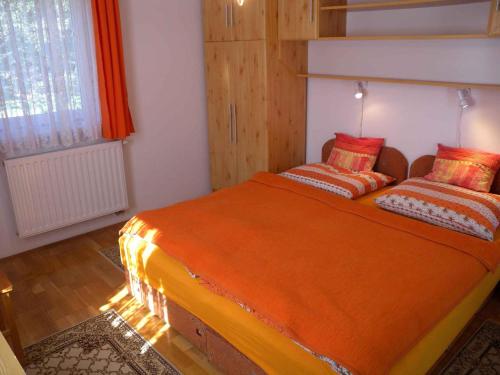 une chambre avec un grand lit orange avec deux oreillers dans l'établissement Apartment Zalakaros 5, à Zalakaros