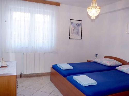 1 Schlafzimmer mit 2 Betten mit blauer Bettwäsche und einem Kronleuchter in der Unterkunft Apartment in Omisalj/Insel Krk 34661 in Omišalj
