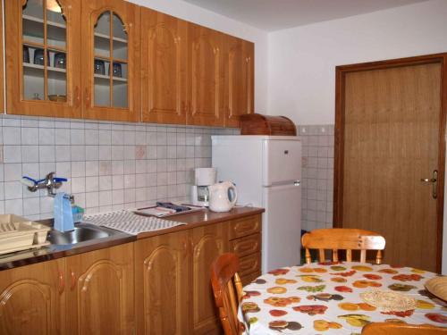 eine Küche mit einem Tisch und einem weißen Kühlschrank in der Unterkunft Apartment in Omisalj/Insel Krk 34661 in Omišalj