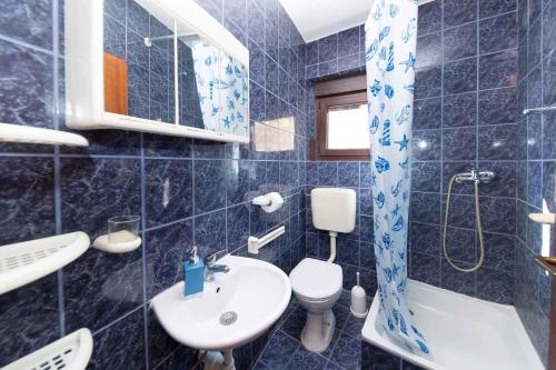 uma casa de banho em azulejos azuis com um lavatório e um WC em Apartments in Crikvenica 31165 em Crikvenica