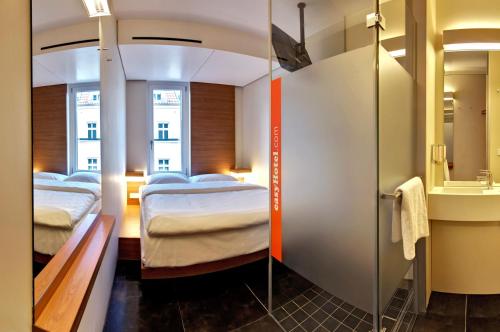 una camera d'albergo con due letti e uno specchio di easyHotel Berlin Hackescher Markt a Berlino