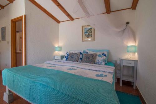a bedroom with a bed with blue sheets and two lamps at Apartments in Veli Losinj 33624 in Veli Lošinj