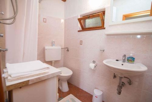 a white bathroom with a sink and a toilet at Apartments in Veli Losinj 33624 in Veli Lošinj