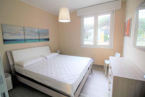 1 dormitorio con 1 cama, 1 mesa y 2 ventanas en Apartments in Rosolina Mare 24915, en Rosolina Mare
