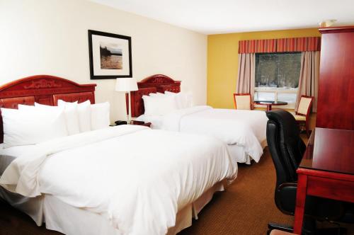 a hotel room with two beds and a desk at Trend Mountain Hotel & Conference Centre in Tumbler Ridge