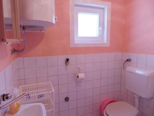 a bathroom with a toilet and a sink and a window at Apartment Karlobag/Velebit Riviera 27804 in Karlobag