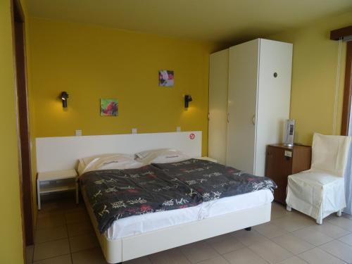 a bedroom with a bed and a white chair at Hostellerie Daiseldaele in Dadizele