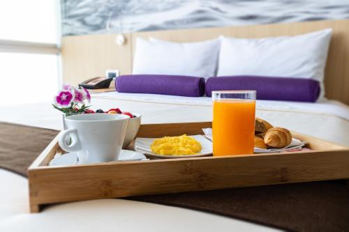 a tray of food and orange juice on a bed at Palmetto Hotel Business San Borja in Lima