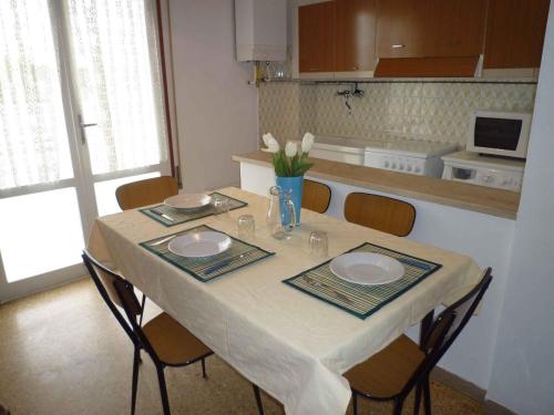 einen Tisch mit zwei Platten und eine Vase Blumen darauf in der Unterkunft Apartments in Eraclea Mare 25611 in Eraclea Mare