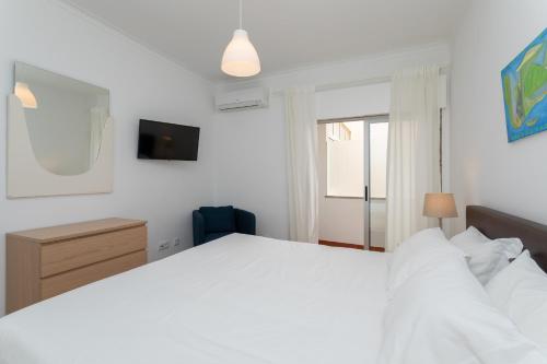 une chambre avec un grand lit blanc et une fenêtre dans l'établissement AL - Apartamentos Vista Mar, à Quarteira