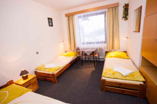 Habitación con 3 camas, mesa y ventana en Holiday home Benecko/Riesengebirge 2230, en Benecko