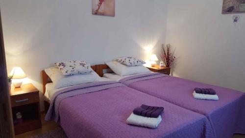 a bedroom with two beds with purple sheets and towels at Apartment in Matulji 17036 in Matulji
