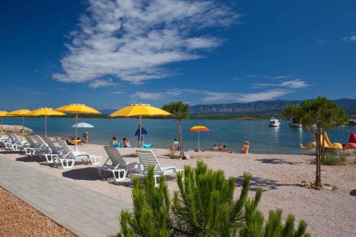 una playa con sillas y sombrillas y gente en ella en Apartments in Silo - Insel Krk 13442, en Šilo