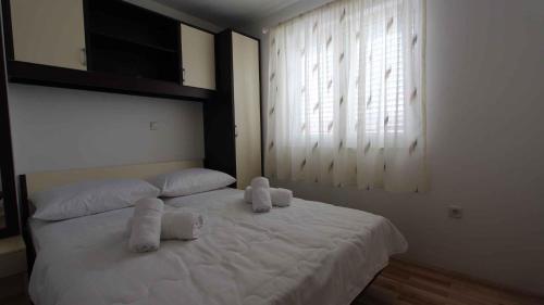 a bedroom with a white bed with two stuffed animals on it at Apartment in Malinska/Insel Krk 13118 in Sveti Vid-Miholjice