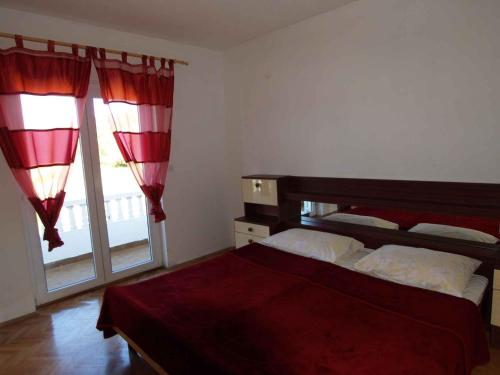 a bedroom with a bed with red curtains and a window at Apartment in Rab/Insel Rab 16489 in Palit