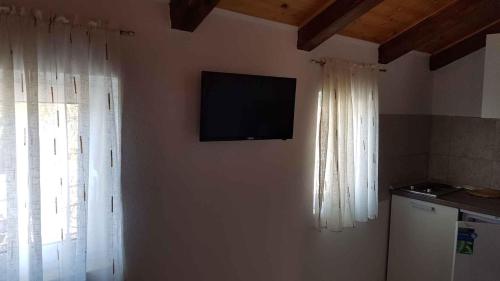 a television on a wall in a kitchen with curtains at One-Bedroom Apartment in Baric Draga II in Barić Draga