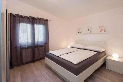 a white bedroom with a bed with a window at Apartment in Rabac 16817 in Rabac