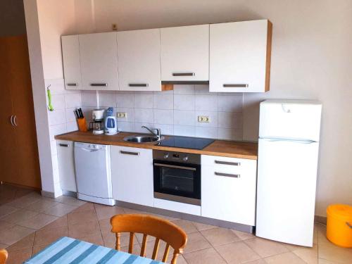 una cucina con armadi bianchi, lavandino e frigorifero di Apartment in Okrug Gornji with Two-Bedrooms 2 a Trogir