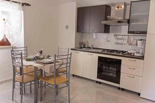 a kitchen with a table and chairs and a stove at Holiday home in Moscenice 15209 in Mošćenice