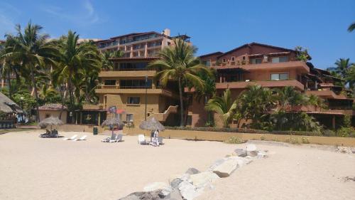 a resort with a sandy beach with chairs and palm trees at Villas del Sol en Los Tules in Puerto Vallarta