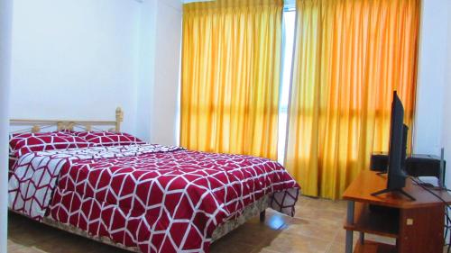 a bedroom with a red and white bed and a television at Departamento Carabelas de Colón in Playas