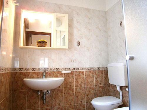 a bathroom with a sink and a toilet and a mirror at Apartment in Bibione 24583 in Bibione