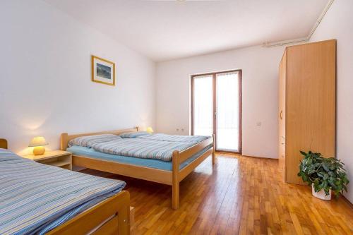 - une chambre avec 2 lits et une grande fenêtre dans l'établissement Apartments Dragica, à Valbandon