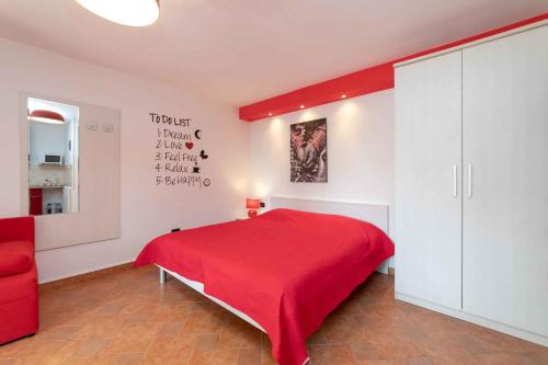 a bedroom with a red bed and a red chair at Studio Apartment in Vrsar I in Vrsar