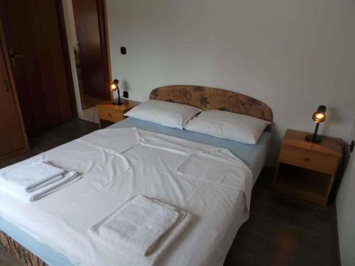 a bedroom with a bed with white sheets and two lamps at Apartment in Novi Vinodolski 15375 in Novi Vinodolski