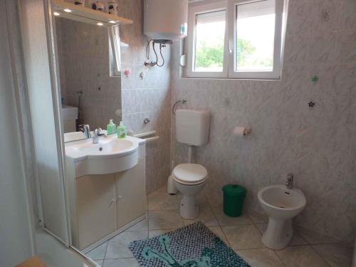 a bathroom with a sink and a toilet and a window at Apartment in Novi Vinodolski 15375 in Novi Vinodolski