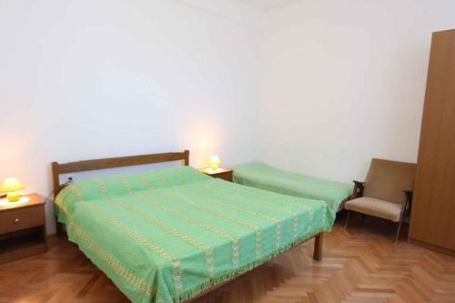 a bedroom with a green bed and a chair at Apartment Silo 19 in Šilo