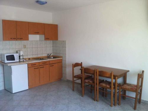 a kitchen with a table and chairs and a microwave at Apartment Lopar 3 in Lopar