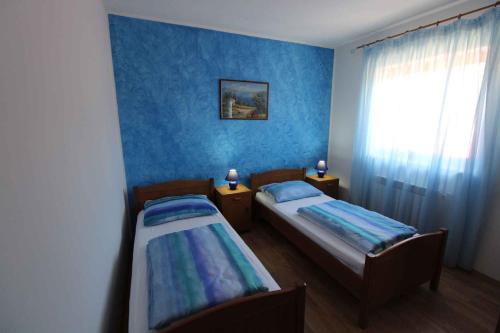 two beds in a room with blue walls and a window at House and Apartments in Labin 8758 in Strmac