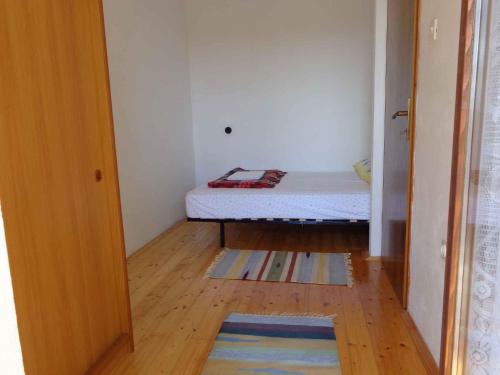 a small bedroom with a bed and a wooden floor at Apartment Sv. Marina 1 in Sveta Marina