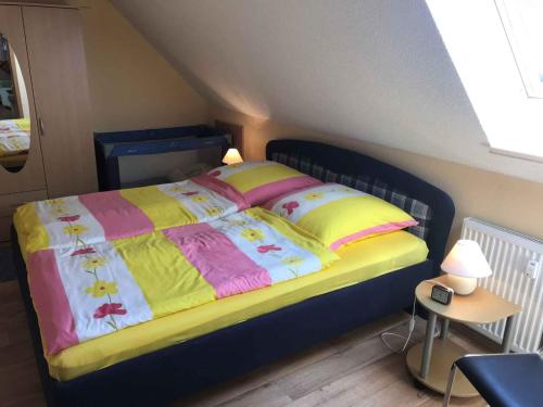 um quarto com uma cama com um cobertor amarelo e rosa em Apartment Gingst 1 em Haidhof