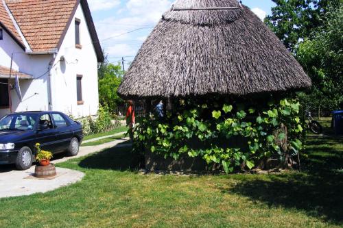 un cenador cubierto de hierba en un patio con coche en Holiday home Abadszalok/Theiss-See 20563, en Bánomszőlő