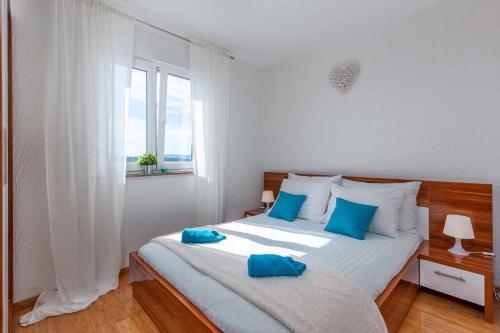 a bedroom with a large bed with blue pillows on it at Apartment Dramalj 31 in Dramalj